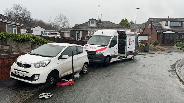 Mobile Tyre Solutions van performing emergency tyre replacement on white Kia outside customer's home