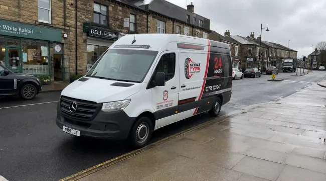Mobile Tyre Solutions Mercedes Sprinter mobile tyre fitting van parked on Horsforth Town Street in Leeds, UK during rainy weather, providing emergency roadside tyre replacement and mobile tyre repair services.