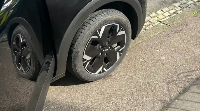 Mobile tyre fitter replacing tyre on black Kia SUV at roadside in Huddersfield