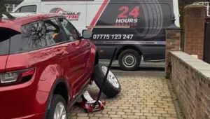 Mobile Tyre Solutions fitter replacing tyre on red Range Rover at customer's driveway