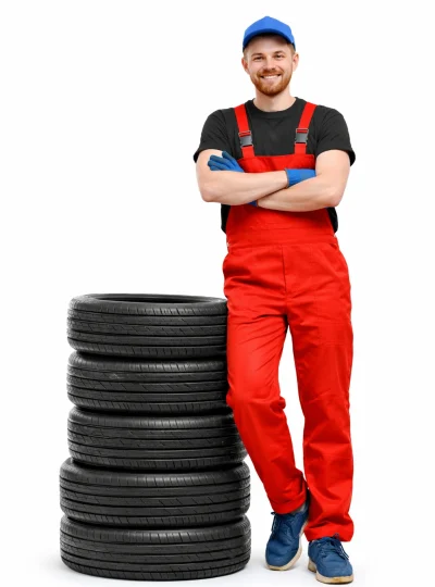 Mobile tyre fitter standing confidently next to a stack of fitting tyres ready for installation